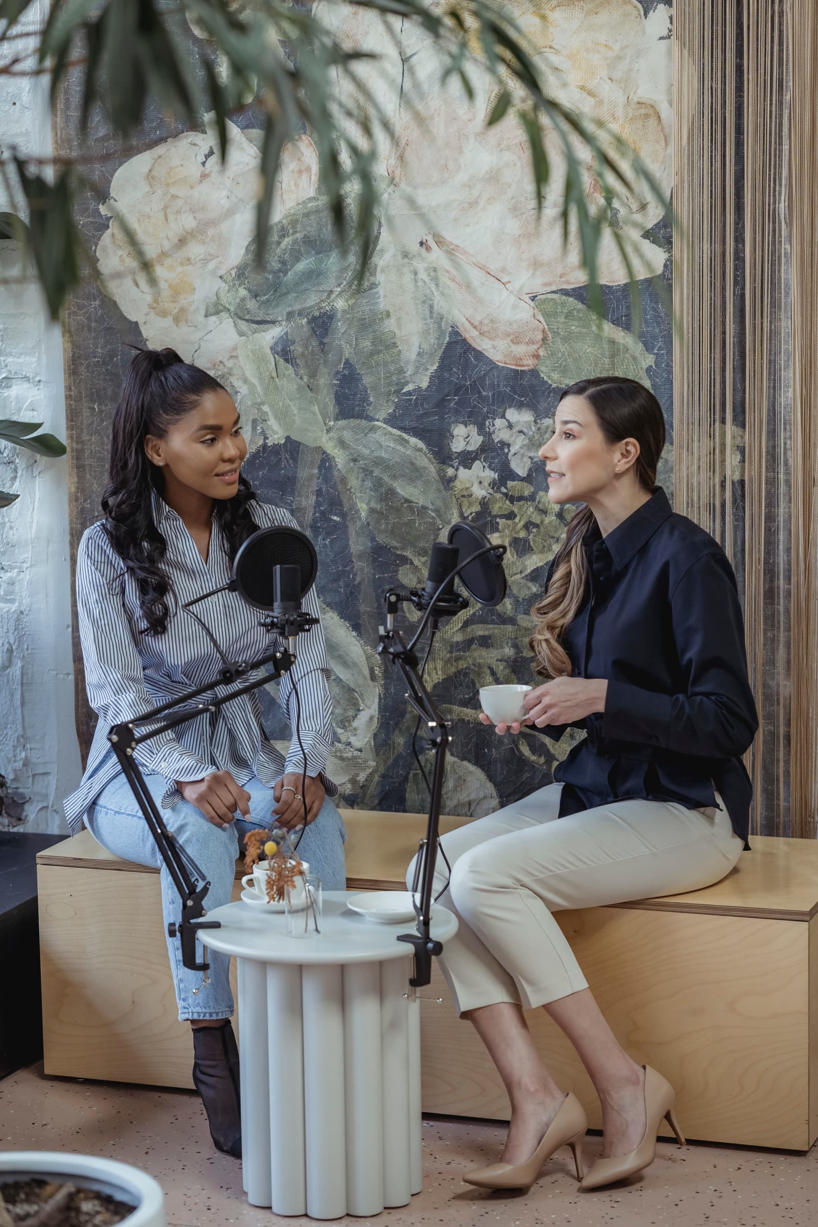 Two people seated face to face at podcast mics, deep in conversation